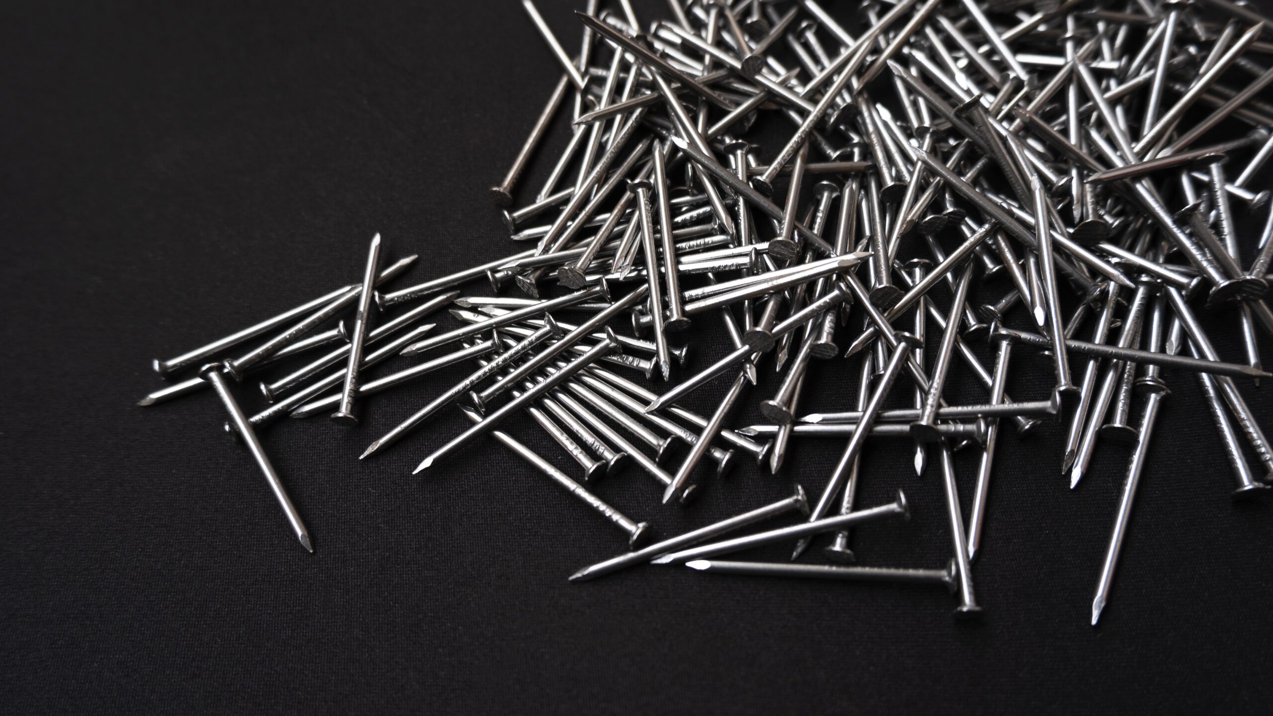 panoramic shot of a pile of steel nails on a black background